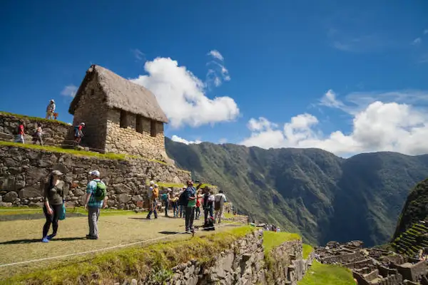 Visitantes caminhando pelas trilhas de pedra e terraços próximos à Casa do Guardião em Machu Picchu